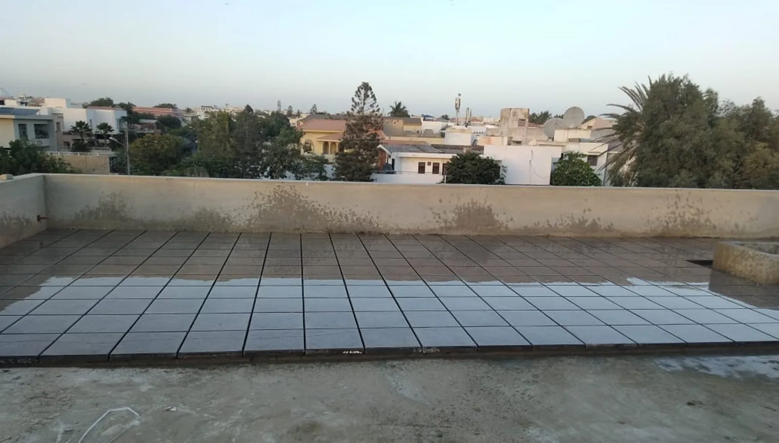 Cement finish roof heat insulation tiles laid across a flat Karachi rooftop at dusk