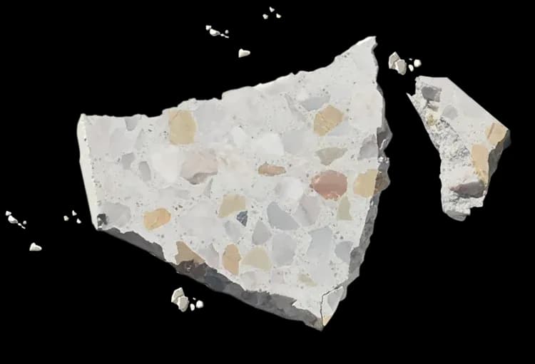 Broken terrazzo tile showing marble aggregate suspended through the full depth of the cement matrix