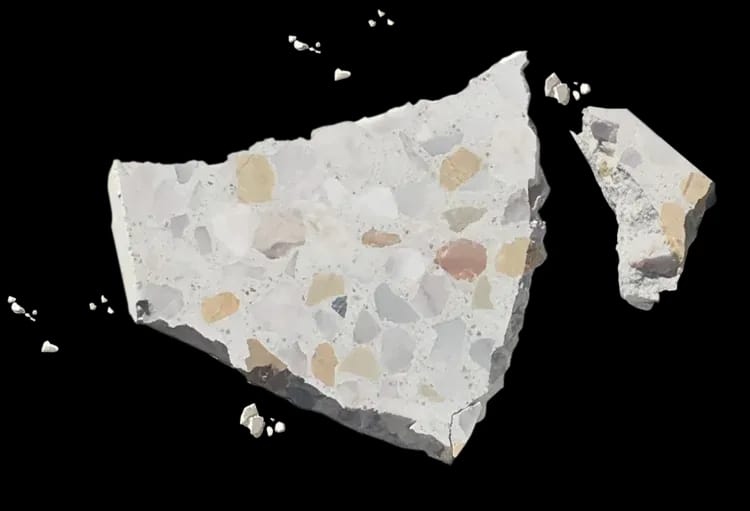 Broken terrazzo tile showing marble aggregate suspended through the full depth of the cement matrix