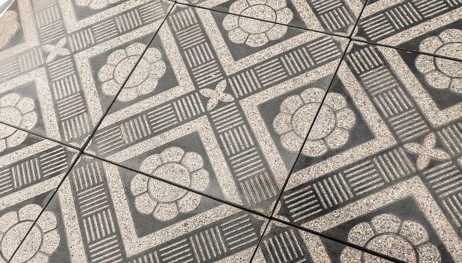Grey patterned paving tiles carrying a geometric medallion across four units