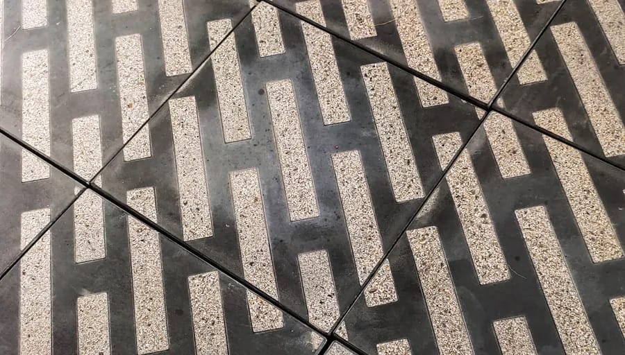 Charcoal paving with pale hatched bars cast into an exposed aggregate face