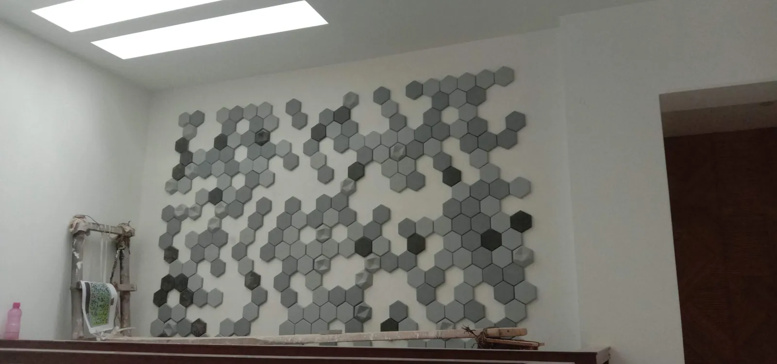 Khewra hexagonal 3D concrete tiles in mixed greys set as a scattered field on a plain white wall