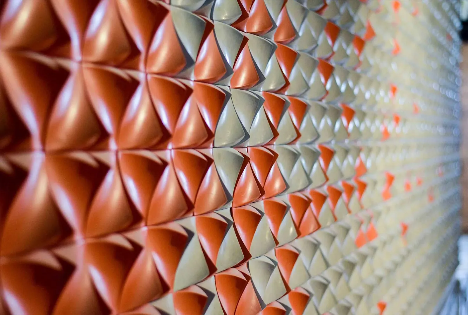 Lehr 3D concrete tiles in cream and terracotta, each unit scooped into a cone so the field reads as a wave