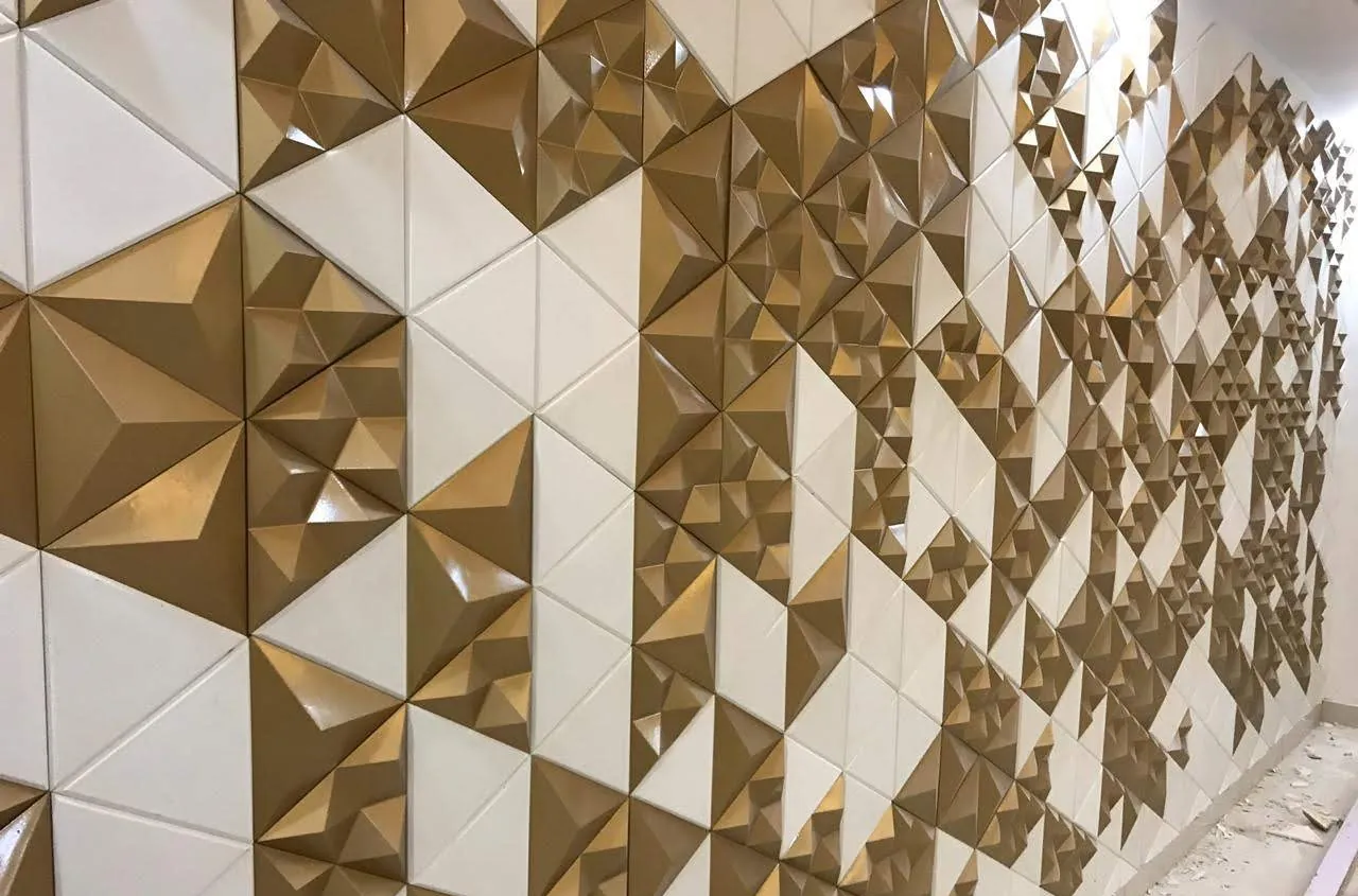 Mathlath 3D concrete wall tiles in gold and white, pyramidal facets catching a raking light