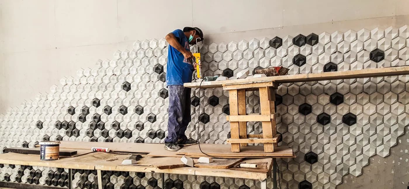 Installer fixing hexagonal 3D concrete wall tiles at Bahria Town Tower