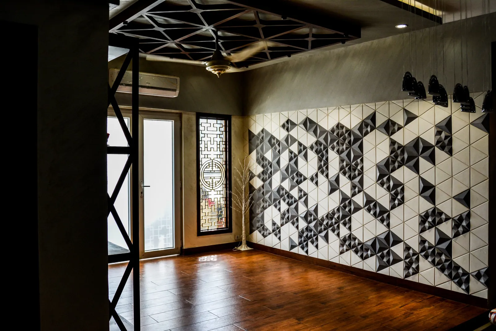 Black and white 3D concrete wall tiles forming a faceted feature wall in a dark interior