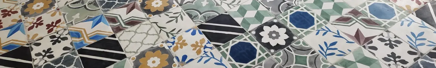 Moroccan pattern cement tiles laid on the diagonal in ochre, blue, green and charcoal on a cream ground