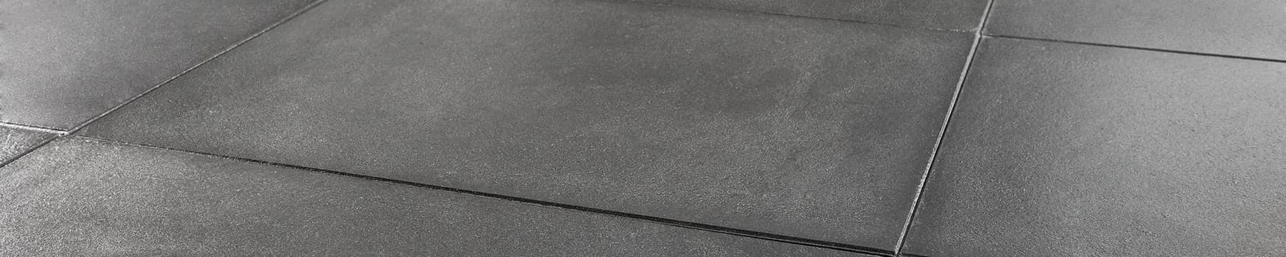 Charcoal pigmented concrete floor tiles in low raking light