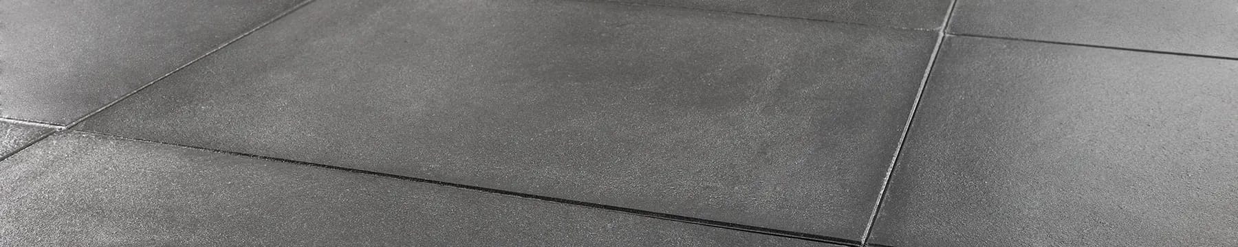 Charcoal pigmented concrete floor tiles in low raking light