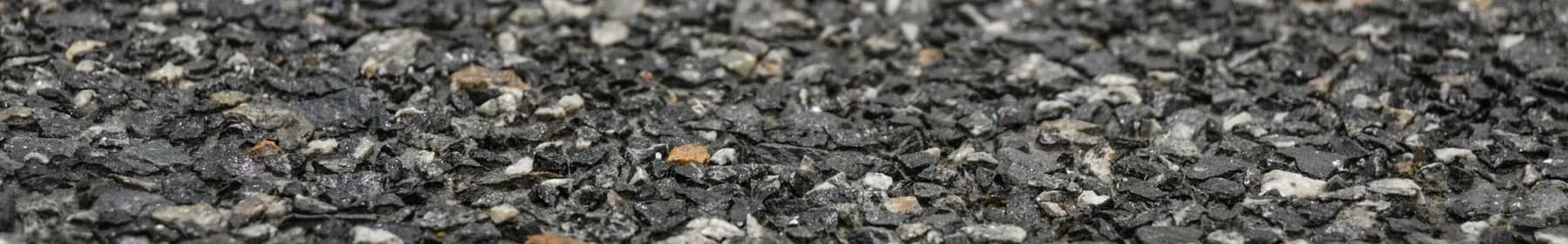 Washed terrazzo close up, charcoal aggregate with pale grey and tan chips standing proud of the cement matrix