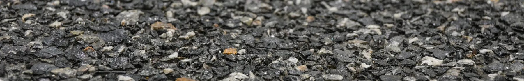 Washed terrazzo with dark aggregate standing proud of the cement matrix, pale grey and tan chips catching the light